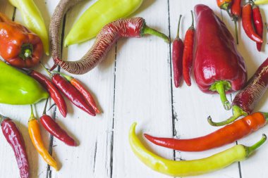 Eski beyaz ahşap masa üzerinde çeşitli renkli ve taze biber (paprika) türleri. Yüksek açı görünümü