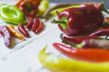 Eski beyaz ahşap masa üzerinde çeşitli renkli ve taze biber türleri (paprika).