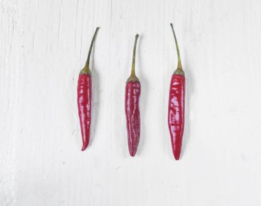 Güzel beyaz masada üç kırmızı, sıcak kırmızı biber. Yüksek açı görünümü