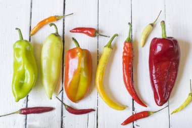 Eski beyaz ahşap masa üzerinde çeşitli renkli ve taze biber (paprika) türleri. Yüksek açı görünümü