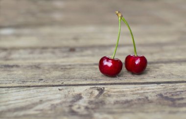 Eski ahşap masada iki taze ve lezzetli kiraz..