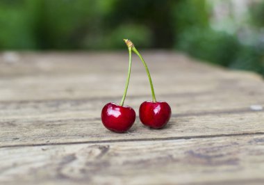 Eski ahşap masada iki taze ve lezzetli kiraz..