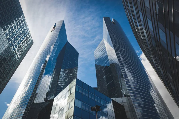 Paris, Fransa - 02 Ekim 2018: Gökdelen cam cepheleri açık güneşli bir günde mavi gökyüzünde güneş ışınları. Paris iş bölgesi La Defense 'daki modern binalar. Ekonomi, finans, iş faaliyeti konsepti. Alt görünüm.