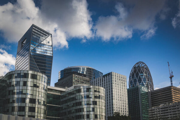 PARIS, FRANCE - 02 OCTOBER 2018:Skyscraper glass facades on a bright sunny day with sunbeams in the blue sky. Modern buildings in Paris business district La Defense. Economy, finances, business activity concept. Bottom up view.