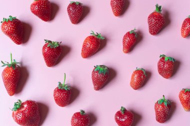 Pembe arka planda taze ve sulu kırmızı çilek deseni. Yüksek açı görünümü