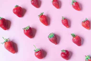 Pembe arka planda taze ve sulu kırmızı çilek deseni. Yüksek açı görünümü 