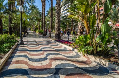 ALICANTE, İspanya - 30 Aralık 2018: İspanya 'nın en popüler yaya yollarından biri olan Alicante kentindeki bir gezinti alanı olan Paseo de la Explanada' da yürüyen insanlar.