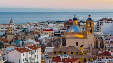 Alacakaranlıkta Alicante şehir manzarası, arka planda deniz olan katedrali gösteriyor