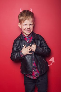 Küçük yakışıklı şeytan boynuzu ve kuyruklu. Çocuk. Cadılar Bayramı. Kırmızı arka plan üzerinde izole stüdyo portre