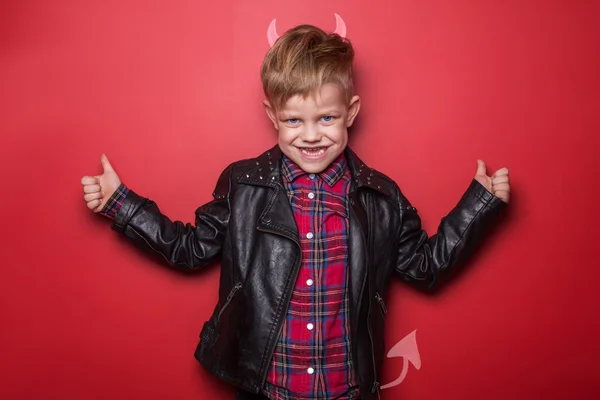 Kleiner schöner Teufel mit Hörnern und Schwanz. Kind. Halloween. Studioporträt isoliert über rotem Hintergrund — Stockfoto