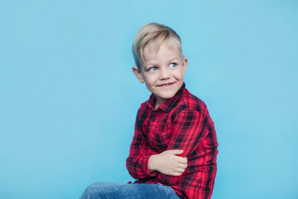 Schöner kleiner Junge mit rotem Hemd. Mode. Studioporträt über blauem Hintergrund — Stockfoto