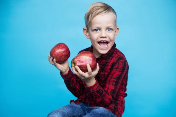 Knappe jongetje met twee rode appels. Studio portret op blauwe achtergrond — Stockfoto