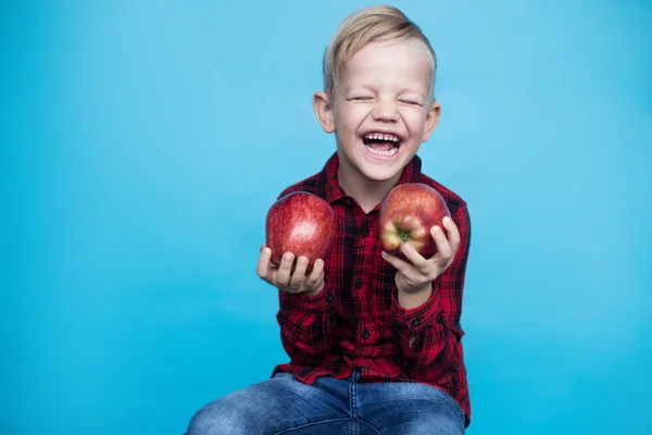 Un niño guapo con dos manzanas rojas. Estudio retrato sobre fondo azul —  Fotos de Stock