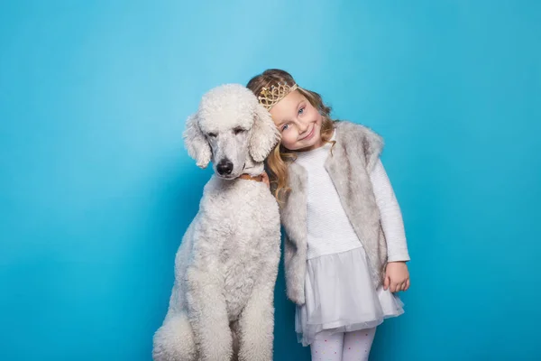 Linda princesinha com cão. Amizade. Animais de estimação. Retrato de estúdio sobre fundo azul — Fotografia de Stock