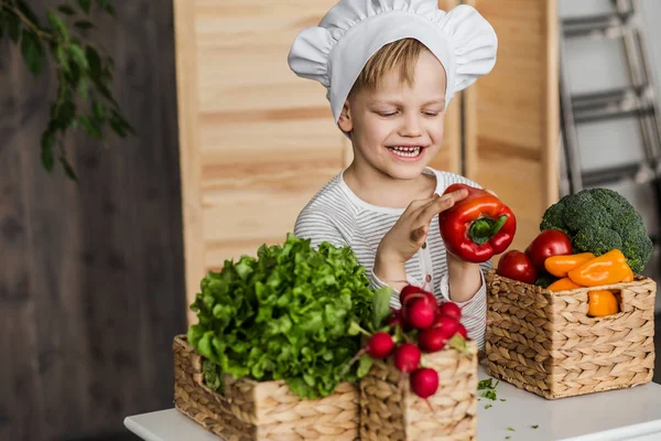 Miúdo bonito de uniforme de chef com legumes. Cozinhar na cozinha em casa. Vegetariano. Alimentos saudáveis — Fotografia de Stock