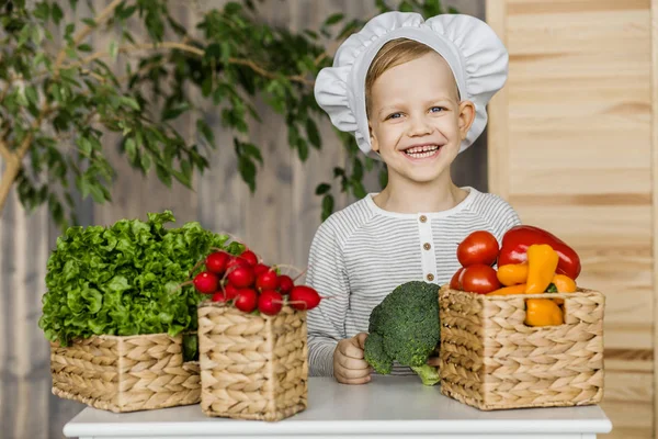 Cute boy in chef uniform with vegetables. Cooking in kitchen at home. Vegetarian. Healthy food — Stock Photo, Image