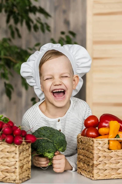 Handsome little kid in chef uniform with vegetables. Cooking in kitchen at home. Vegetarian. Healthy food — Stock Photo, Image