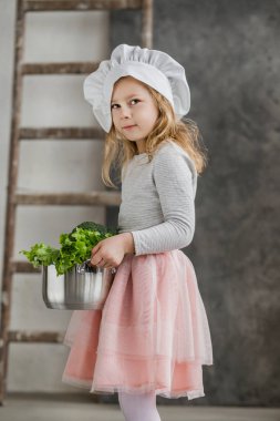 Bir tencere sebze dolu tutan küçük güzel kız. Sağlıklı gıda. Hasat. Küçük ev kadını