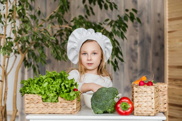 Little beautiful girl making vegetable salad in the kitchen. Healthy food. Little housewife — Stock Photo, Image