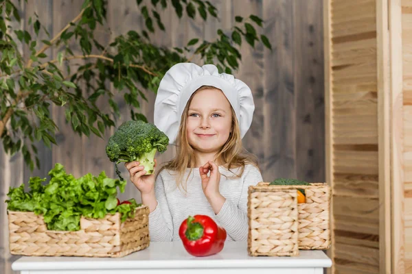 Pequena menina bonita fazendo salada de legumes na cozinha. Comida saudável. Pequena dona de casa — Fotografia de Stock