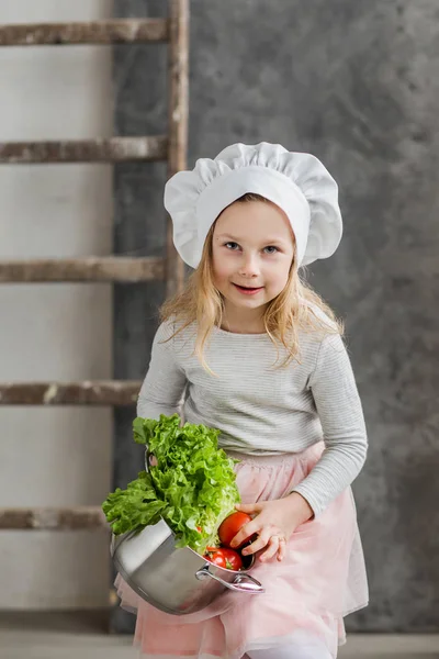 Petite belle fille tenant un pot plein de légumes. Une nourriture saine. Récolte. Petite femme au foyer — Photo