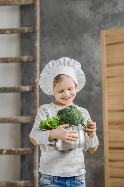 Bonito menino bonito segurando um pote cheio de legumes. Comida saudável. Colheita. Pequeno chef — Fotografia de Stock