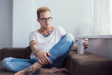 Genç moda model evde kanepede oturan ve kakao içmeye. Sakin ol. Dövme