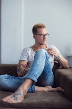 Genç moda model evde kanepede oturan ve kakao içmeye. Sakin ol. Dövme