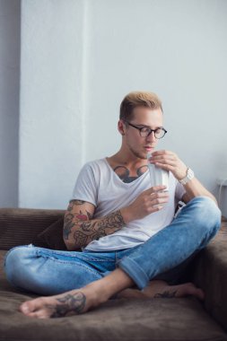 Genç moda model evde kanepede oturan ve kakao içmeye. Sakin ol. Dövme