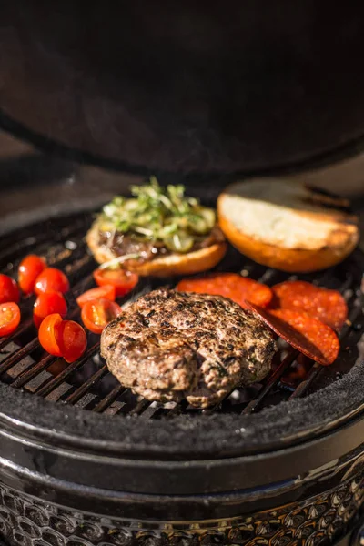 Delizioso cheeseburger con pomodori che cuociono sulla griglia fiammeggiante calda. Barbecue. Ristorante — Foto Stock