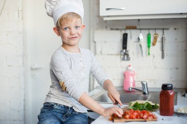 Çocuk Şef mutfakta evde yemek yapıyor. Sağlıklı gıda