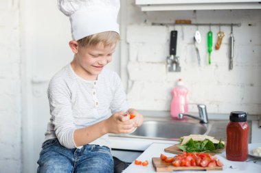 Çocuk Şef mutfakta evde yemek yapıyor. Sağlıklı gıda
