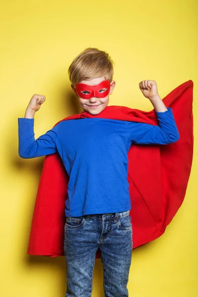 Rapaz de capa e máscara de super-herói vermelho. Super-Homem. Retrato de estúdio sobre fundo amarelo — Fotografia de Stock