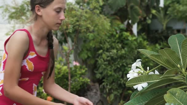 Νεαρό κορίτσι μυρίζοντας λουλούδι στο υποκατάστημα — Αρχείο Βίντεο