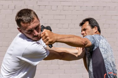 Saldırganın elinden alınan tabancayla saldırıdan korunan bir adam. Krav Maga dövüş tekniklerinin gösterimi, İsrail savunma sistemi