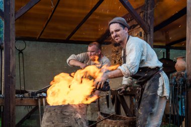 Demirciler, açık ateşin yanındaki eski bir demir ocağında çalışıyor. Yaşayan Tarih Festivali 'nde Ortaçağ Demircilik Atölyesi