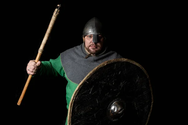 old viking warrior with an ax and shield in a pose of threat. Tall large man posing in simple gray clothing of the early Middle Ages. The costume was created according to archaeological sources, Europe, 9-11 century, the Viking Age