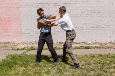 Dövüş sanatları eğitmenleri Krav Maga sokak dövüşlerinde kendini savunma tekniklerini gösterirler. Giysi Bırakma Tekniği