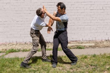 Dövüş sanatları eğitmenleri Krav Maga sokak dövüşlerinde kendini savunma tekniklerini gösterirler. - Evet. Savunma, saldırganın elini engeller ve avucuyla karşı saldırıya geçer.