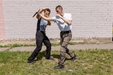 Dövüş sanatları eğitmenleri Krav Maga sokak dövüşlerinde kendini savunma tekniklerini gösterirler. Savunma, saldırgana bıçakla vuruyor.