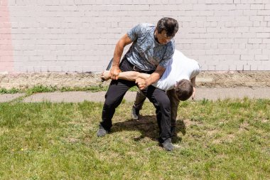 Dövüş sanatları eğitmenleri Krav Maga sokak dövüşlerinde kendini savunma tekniklerini gösterirler. Savunmacı eli bıçakla keser ve saldırganı bıçaklar.