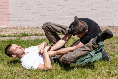 Dövüş sanatları eğitmenleri Krav Maga sokak dövüşlerinde kendini savunma tekniklerini gösterirler. Yakalama pozisyonundan ayrılın. Savunucu rakibin ellerini ve tekmelerini düzeltir.