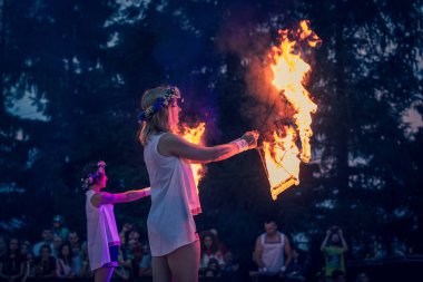Yaz açık hava festivalinde yangın gösterisi. Çelenkli kızlar seyircilerin önünde ateşle dans eder.