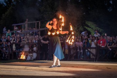 Seyirci kalabalığının arkasında yanan hayranlarla dans eden kız. Yaz açık hava festivalinde yangın gösterisi