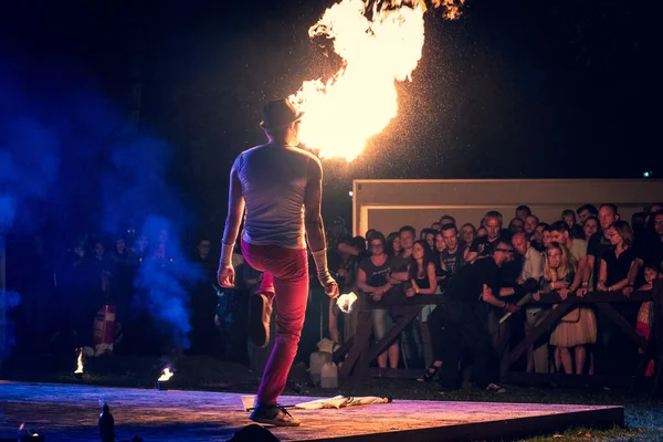 Erkek sanatçı izleyicilere ateş püskürüyor, yaz açık hava festivalinde yangın gösterisi gösterisi gösterisi