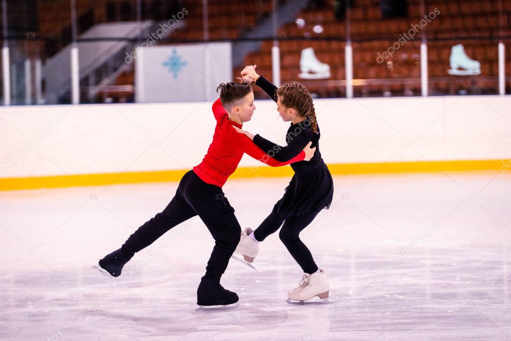 Boy and girl learn to make a path of steps. Training of young beginners in figure skating in the professional ice arena