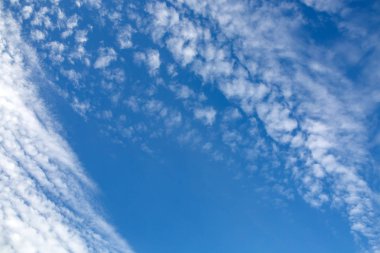 Geniş gökyüzü güneş tarafından vurgulanan süslü kıvırcık bulutlu. Göksel arka planda çok desenli topaç.