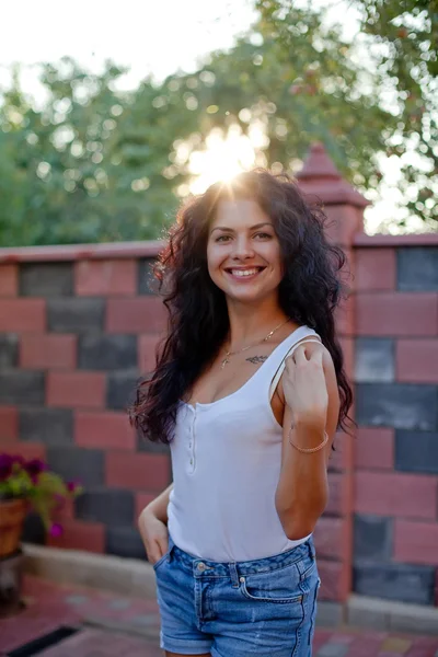 Lächelnde junge brünette Frau posiert im Hof — Stockfoto