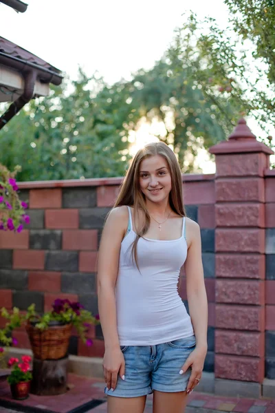 Lächelnde junge brünette Frau posiert im Hof ihrer Residenz in — Stockfoto