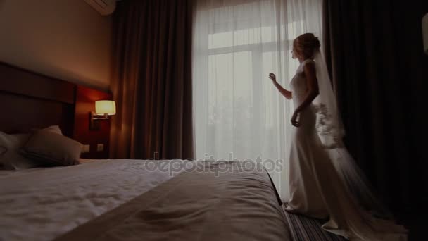 Hermosa novia en vestido blanco magnífico ir a la ventana — Vídeos de Stock